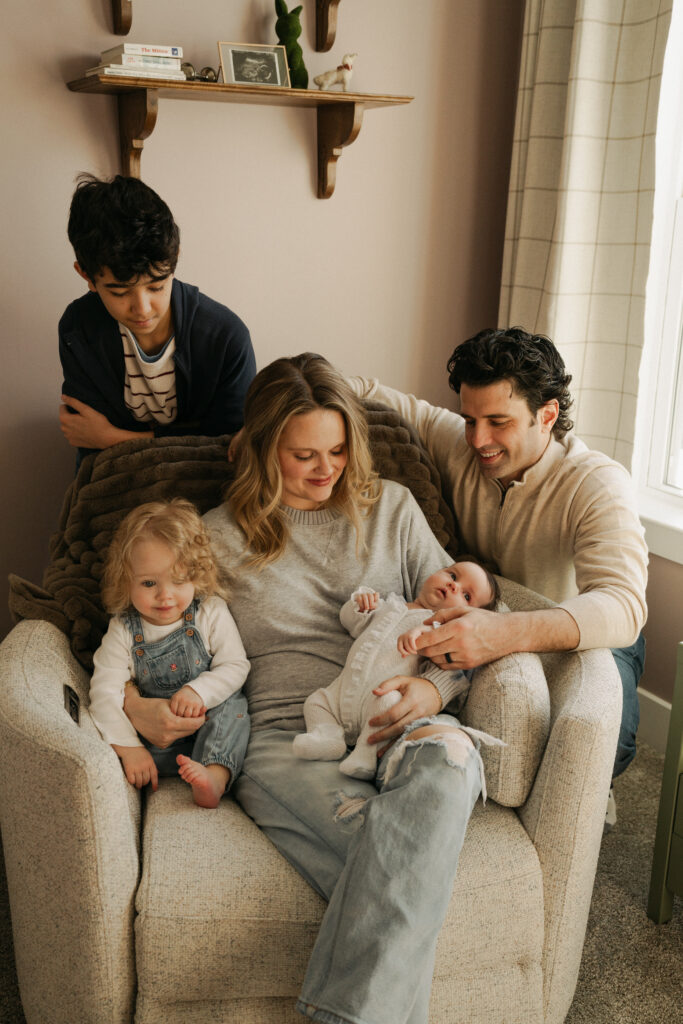 Mother sitting holding newborn with family sitting around her
