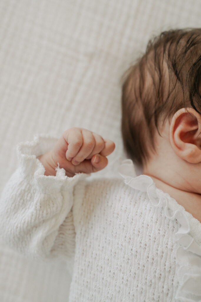 color photo of newborn baby hand closed next to their head