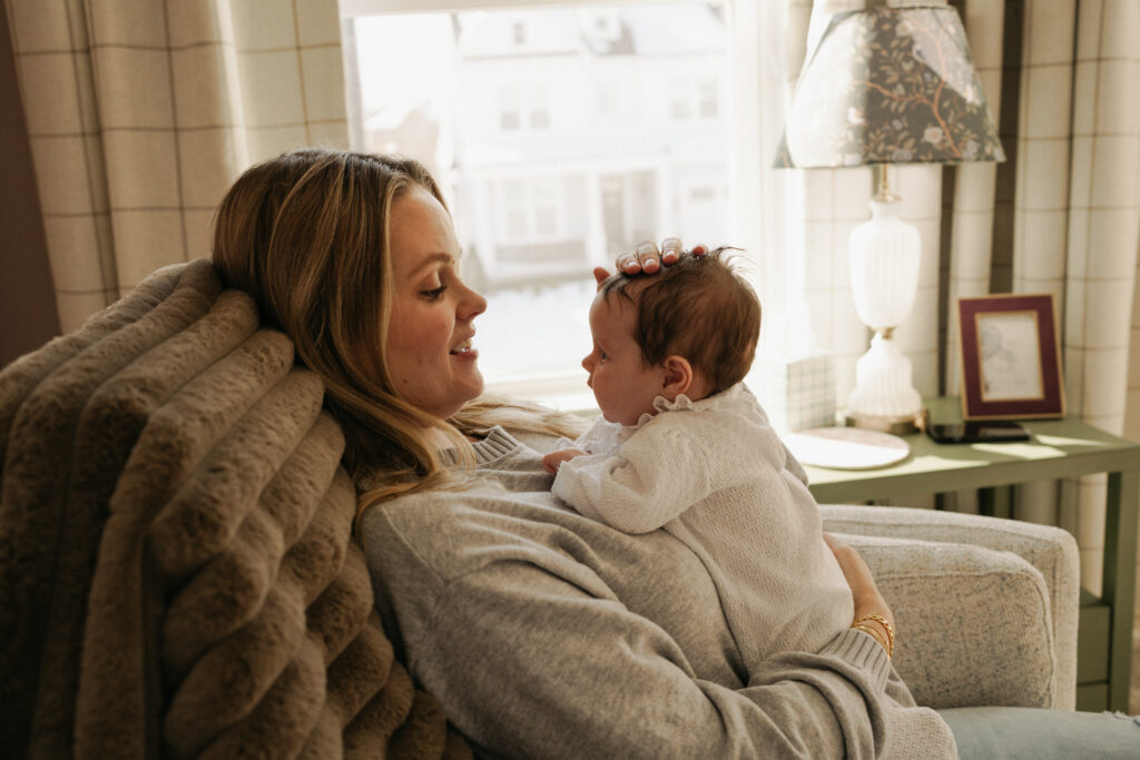 Mom holding newborn on her chest baby girl in a rocking chair 